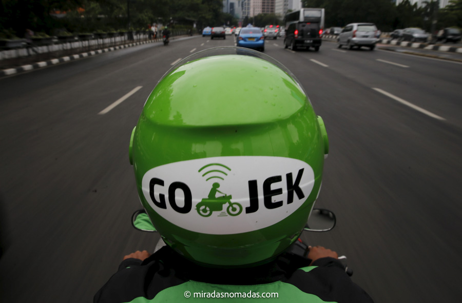 A Gojek driver rides his motorcycle through a business district street in Jakarta